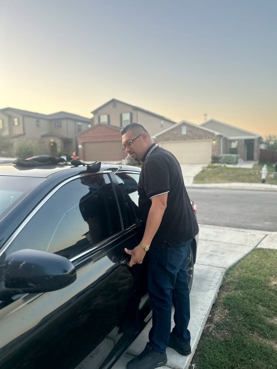 Nick opening a black sedan at dusk in a residential neighborhood